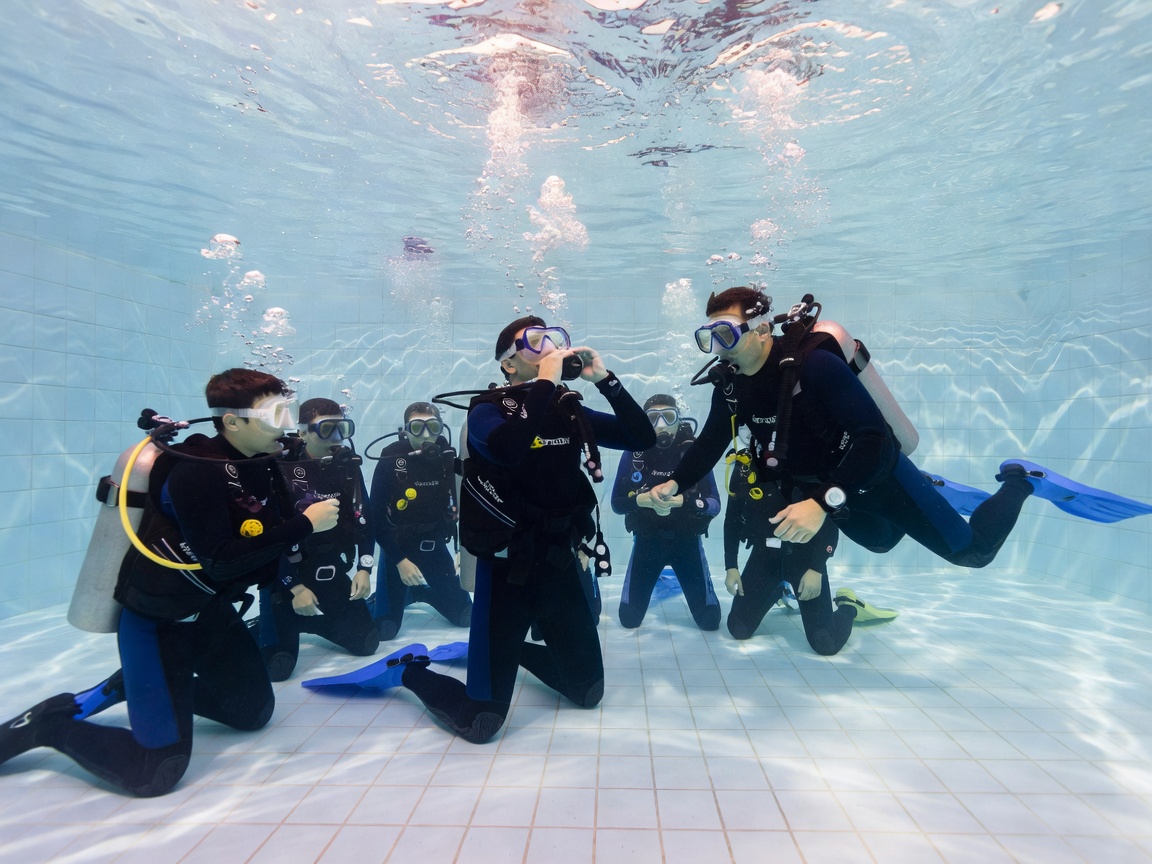 Scuba instructors demonstrating skills to students in a shallow swimming pool